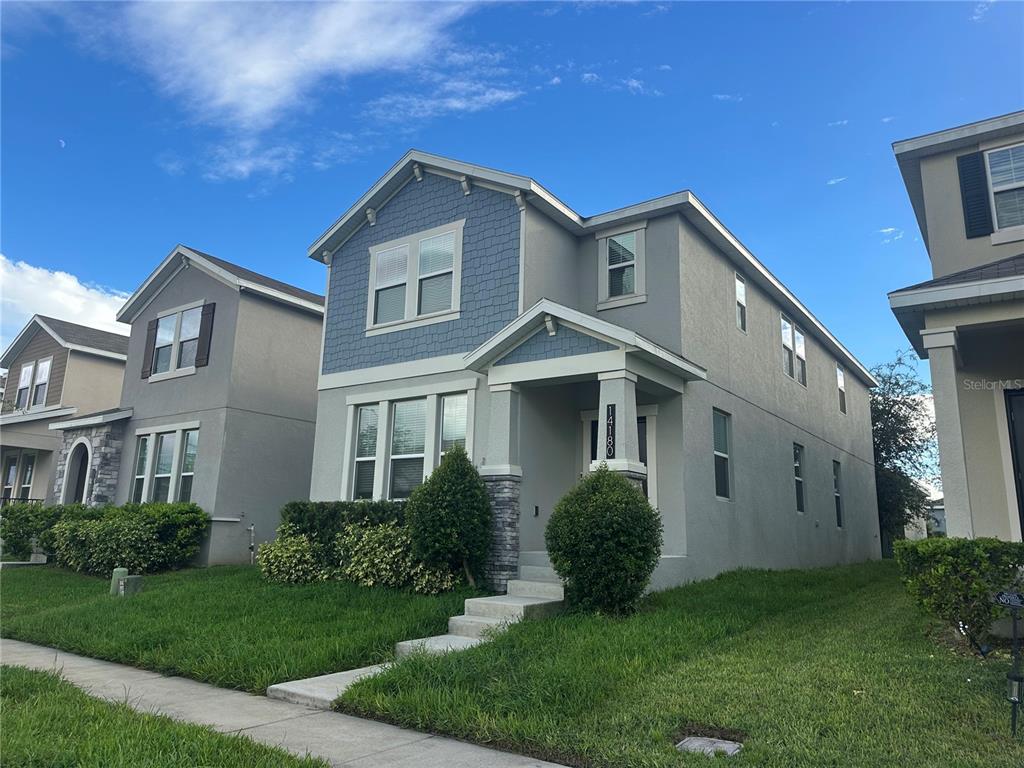 A two-story suburban house with blue shingle siding, gray stucco, and a stone-accented entryway — 14180 TITLE WAY, WINTER GARDEN, FL