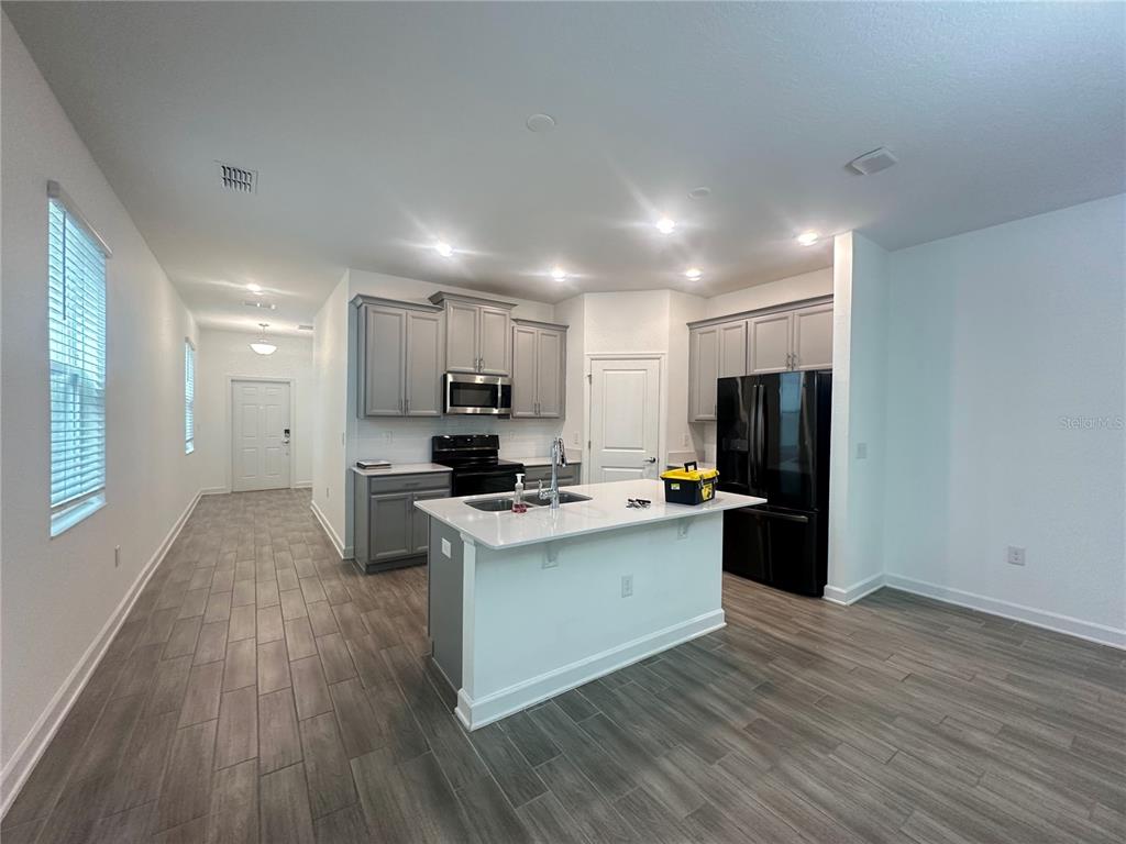 A kitchen features gray cabinets, a white island with a sink, and dark appliances — 14180 TITLE WAY, WINTER GARDEN, FL