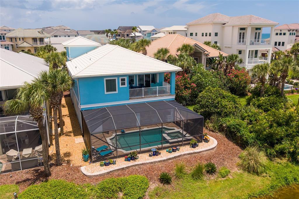 An aerial view of a blue two-story house with a screened-in pool and patio — 550 CINNAMON BEACH LANE, PALM COAST, FL