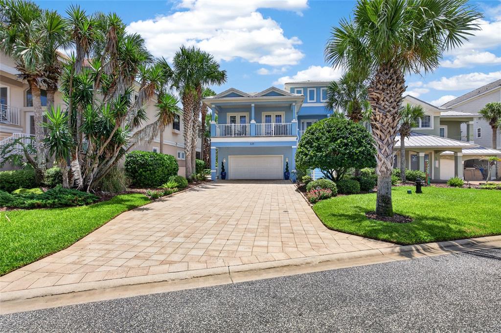 A two-story blue house with a paved driveway, a garage, and palm trees in front — 550 CINNAMON BEACH LANE, PALM COAST, FL