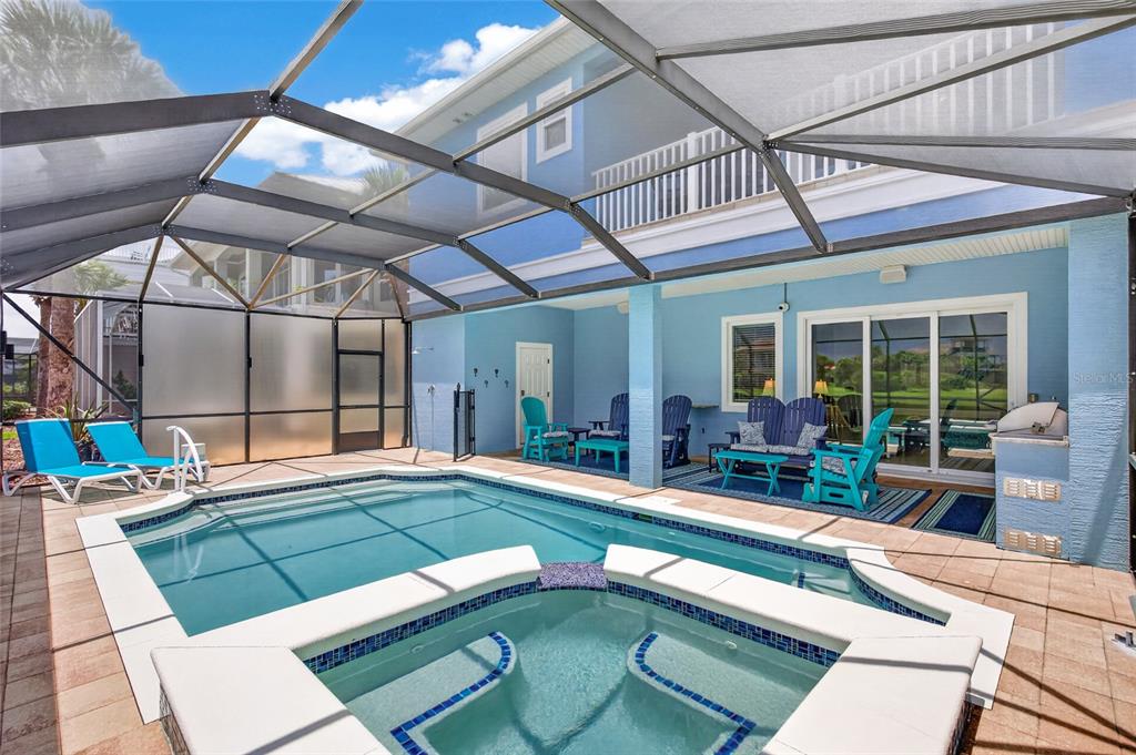 A screened-in pool and hot tub area with blue patio furniture and light blue walls — 550 CINNAMON BEACH LANE, PALM COAST, FL