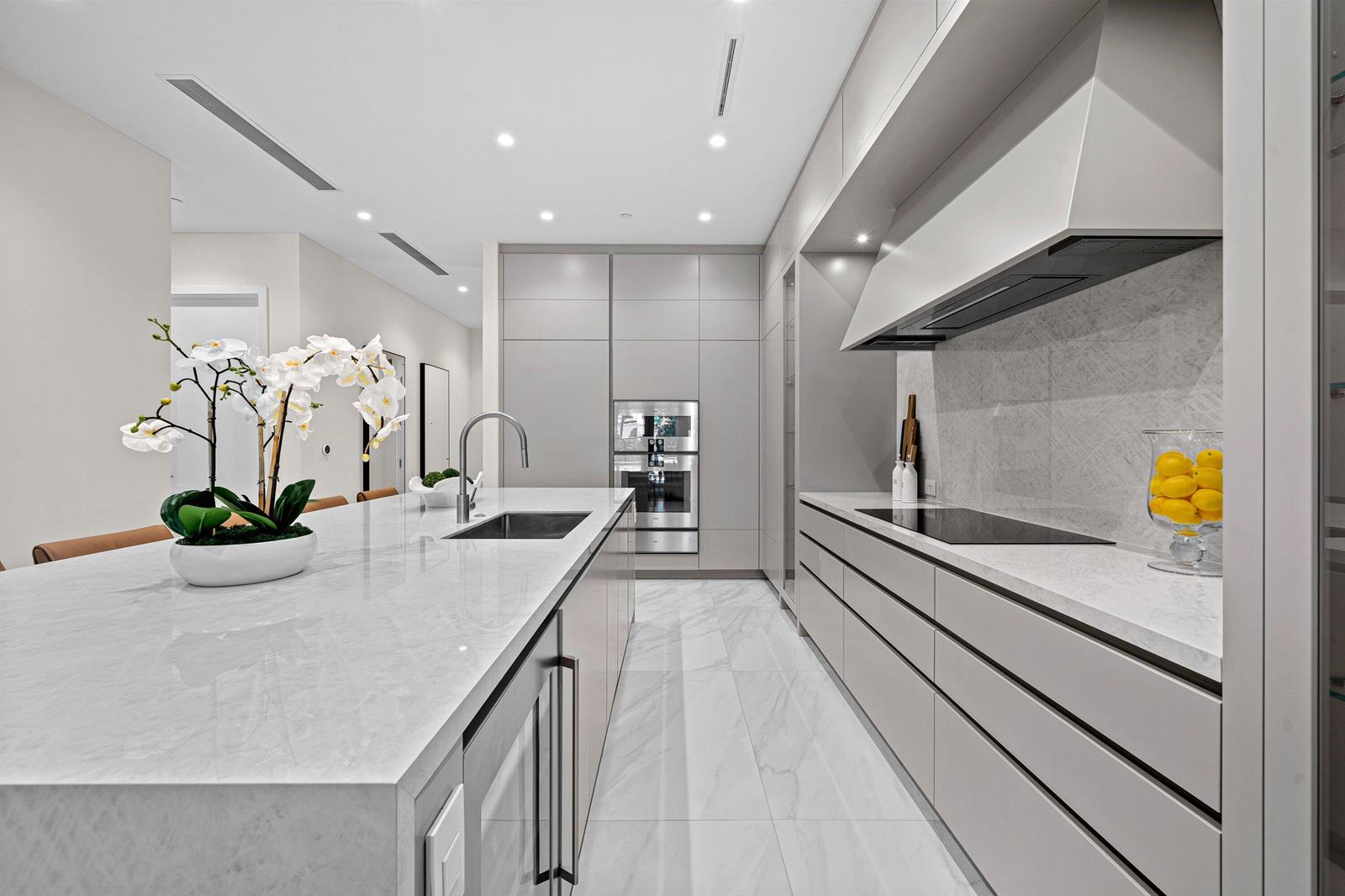 A modern kitchen features a marble island, stainless steel appliances, and light gray cabinetry — 220 SE Mizner Boulevard # 102, Boca Raton FL 33432, BOCA RATON, FL