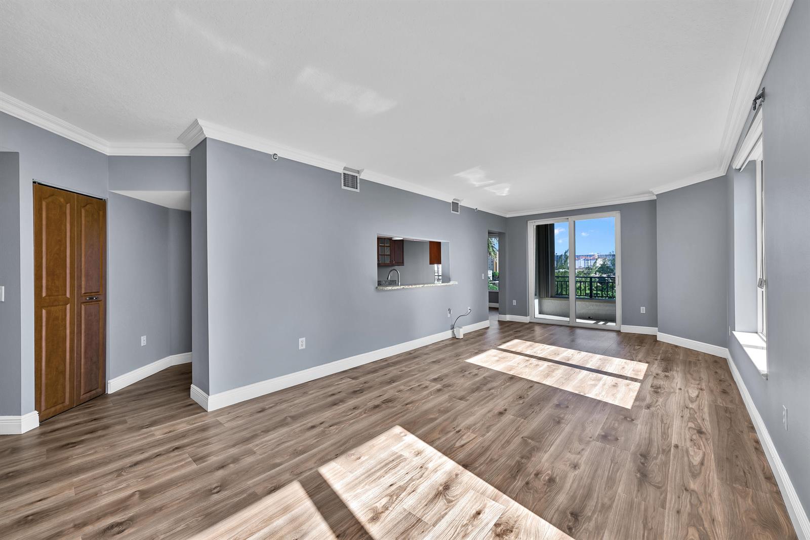 An empty living room with grey walls, wood-look flooring, and a sliding glass door balcony — 2880 NE 14th St Causeway # 413, Pompano Beach FL 33062, POMPANO BEACH, FL