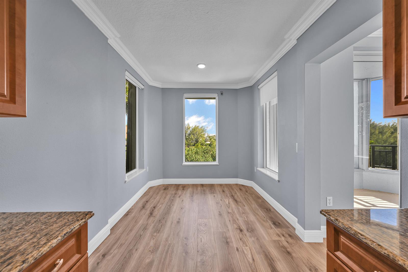 A kitchen breakfast nook with light gray walls, wood-look flooring, and three windows — 2880 NE 14th St Causeway # 413, Pompano Beach FL 33062, POMPANO BEACH, FL