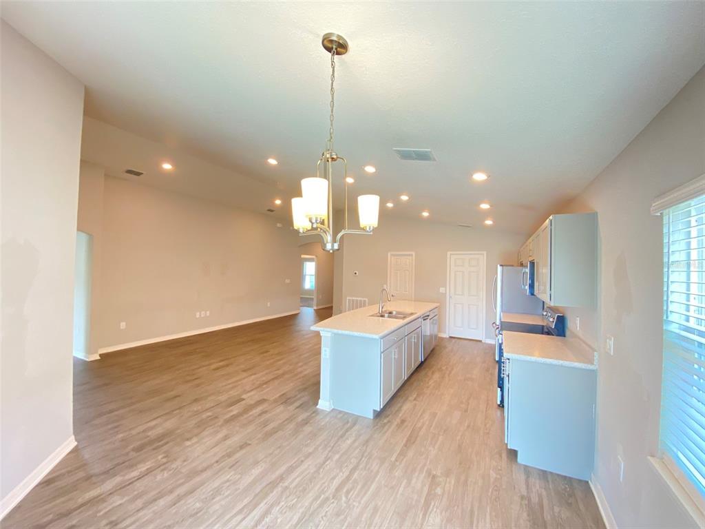 An open-concept kitchen features a central island, light-colored cabinetry, and wood-look flooring — 188 FOXTAIL LOOP, DAVENPORT, FL