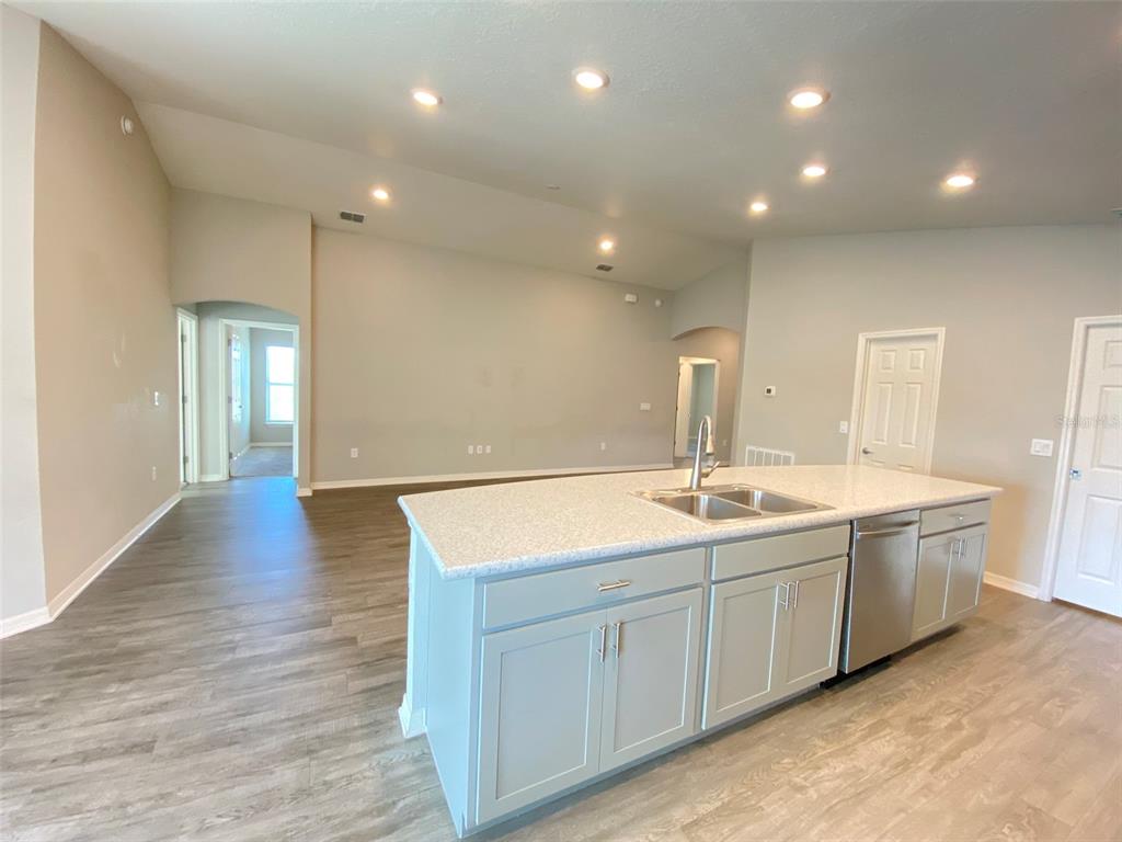 A kitchen island with a double sink sits in an open-concept room with light flooring — 188 FOXTAIL LOOP, DAVENPORT, FL