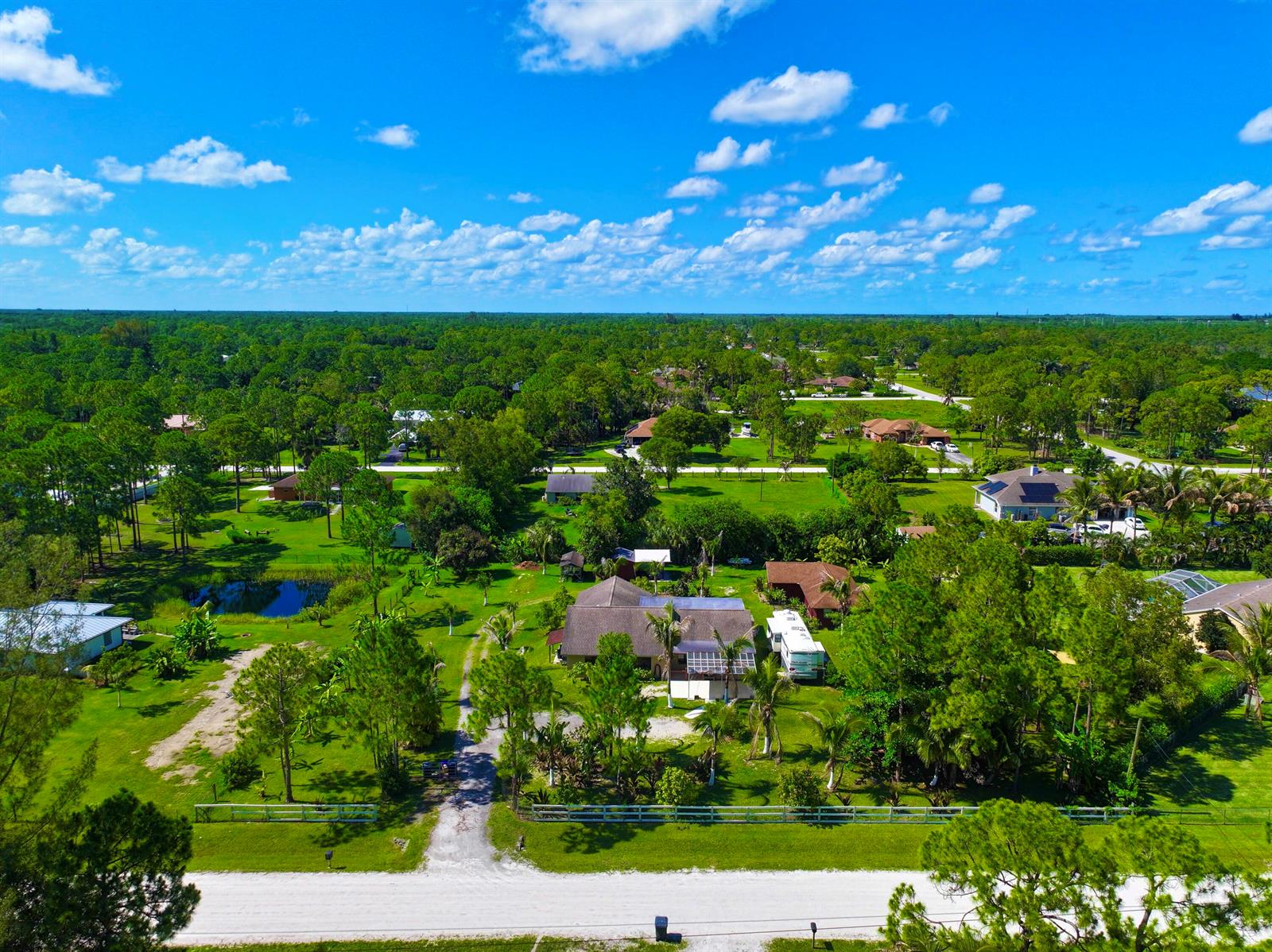 An aerial view of a residential property with a house, driveway, and surrounding wooded landscape — 14539 N 60th Ct Court N, FL 33470, FL