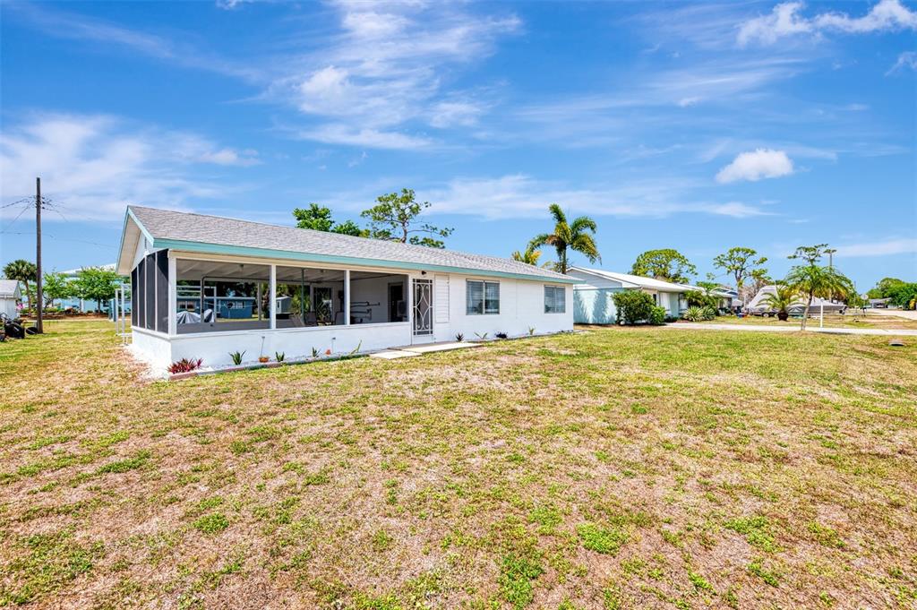 A white single-story house with a screened-in porch sits on a large, grassy lot — 2870 9TH STREET, ENGLEWOOD, FL