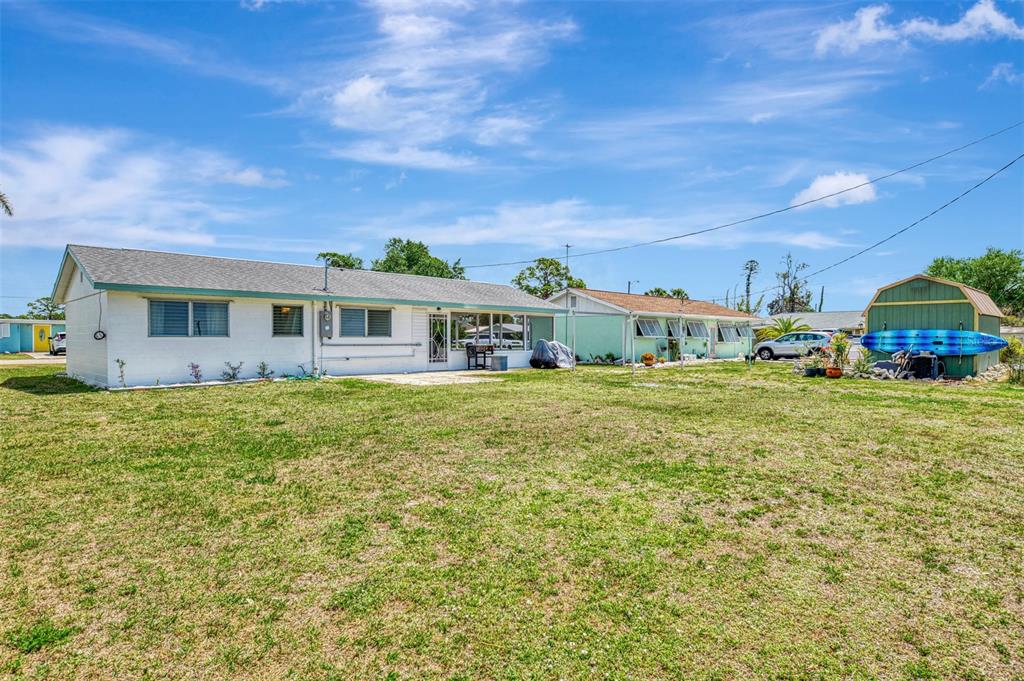 A white single-story house with a large grassy yard and a green storage shed — 2870 9TH STREET, ENGLEWOOD, FL