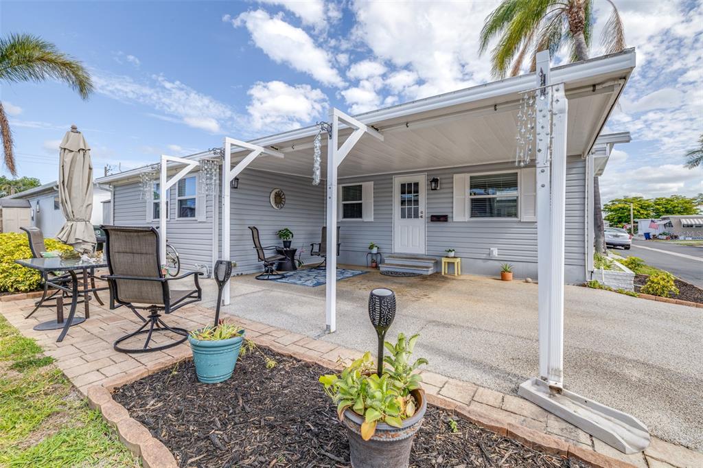 A light gray mobile home features a covered concrete patio, white trim, and a paved driveway — 2712 17TH STREET LANE W, BRADENTON, FL