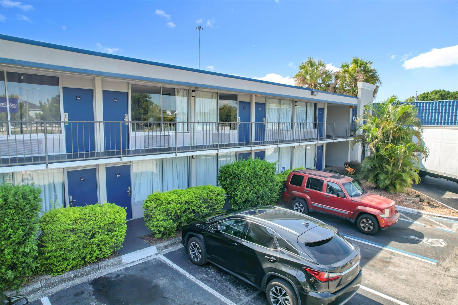 A two-story motel building features blue doors, a metal balcony, and parked vehicles — 4645 N Socrum Loop Road # 101, Lakeland FL 33809, LAKELAND, FL