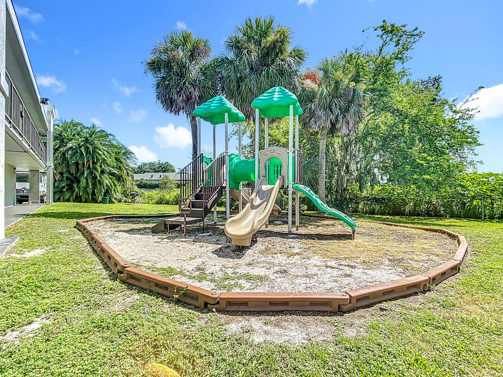 A playground with a slide and climbing structure sits on a sandy lot outdoors — 4645 N Socrum Loop Road # 101, Lakeland FL 33809, LAKELAND, FL