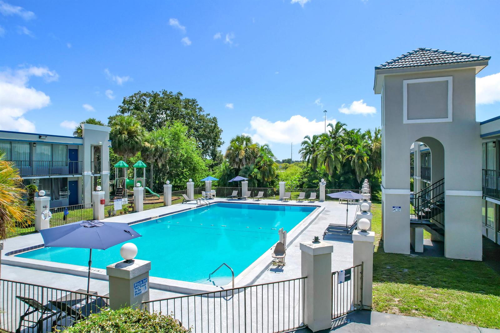 A rectangular outdoor swimming pool is surrounded by a concrete deck, lounge chairs, and buildings — 4645 N Socrum Loop Road # 101, Lakeland FL 33809, LAKELAND, FL