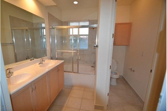 A bathroom features a double vanity with light wood cabinets, a tiled shower-tub, and toilet — 261 Lake Monterey Circle, Boynton Beach FL 33426, BOYNTON BEACH, FL