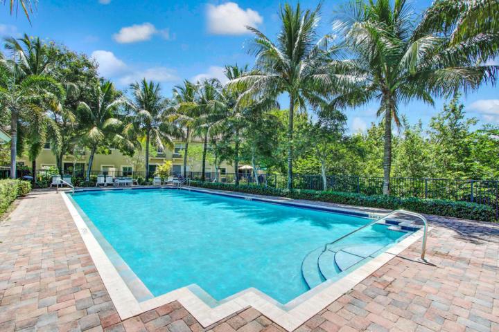 A rectangular swimming pool with a brick paver deck surrounded by palm trees and landscaping — 261 Lake Monterey Circle, Boynton Beach FL 33426, BOYNTON BEACH, FL