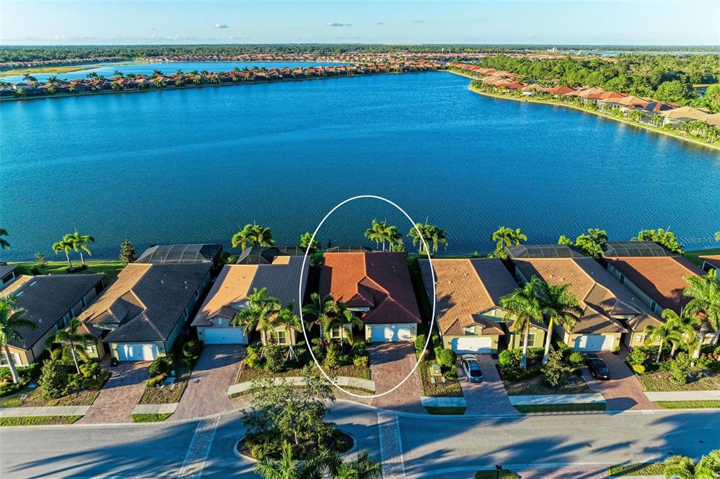 An aerial view shows a house with a red tile roof situated along a lake — 228 MARAVIYA BOULEVARD, NOKOMIS, FL