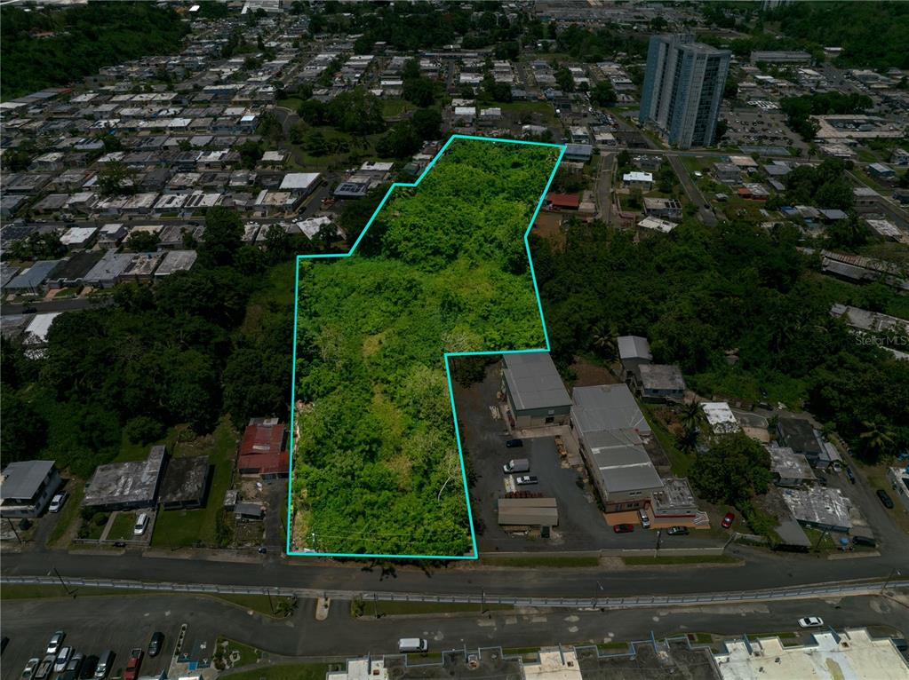 An aerial view shows a vacant, tree-covered lot outlined in blue next to commercial buildings — CLL RAMON FIGUEROA CASTRO SAN ANTON, CAROLINA, PR