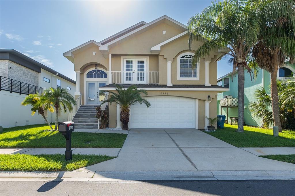 A two-story house with a beige stucco exterior, a two-car garage, and a front balcony — 5416 JOBETH DRIVE, NEW PORT RICHEY, FL