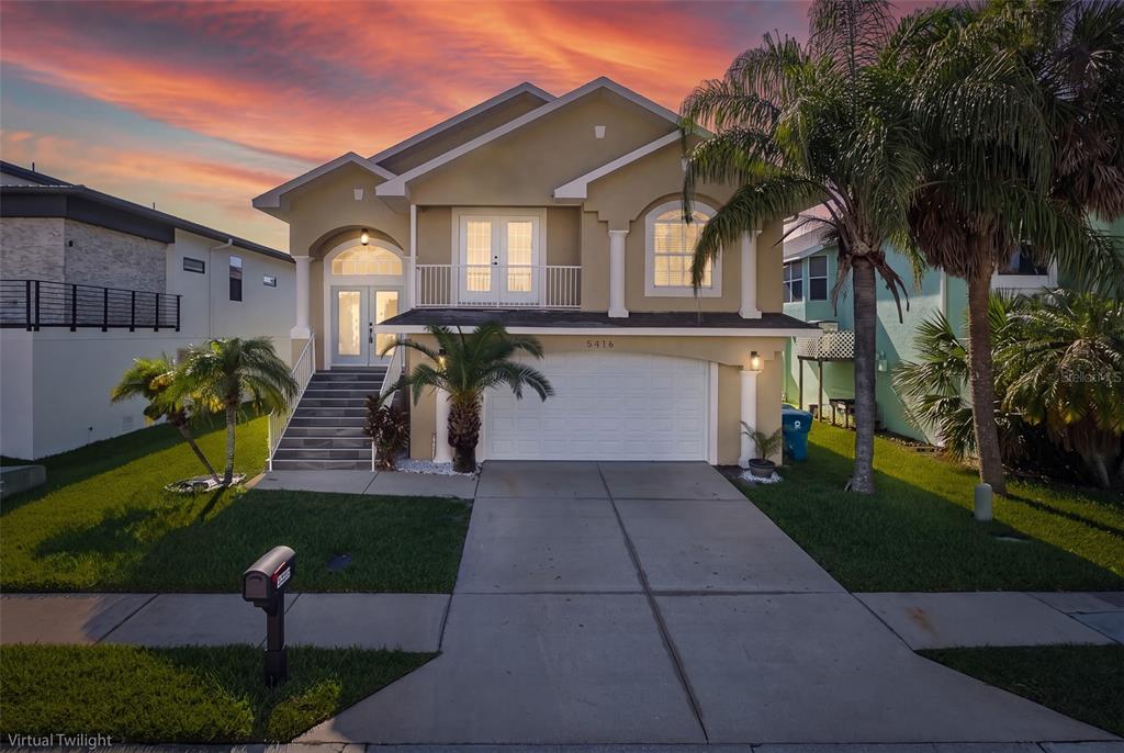 A two-story house with a garage, front stairs, and a balcony under a sunset sky — 5416 JOBETH DRIVE, NEW PORT RICHEY, FL