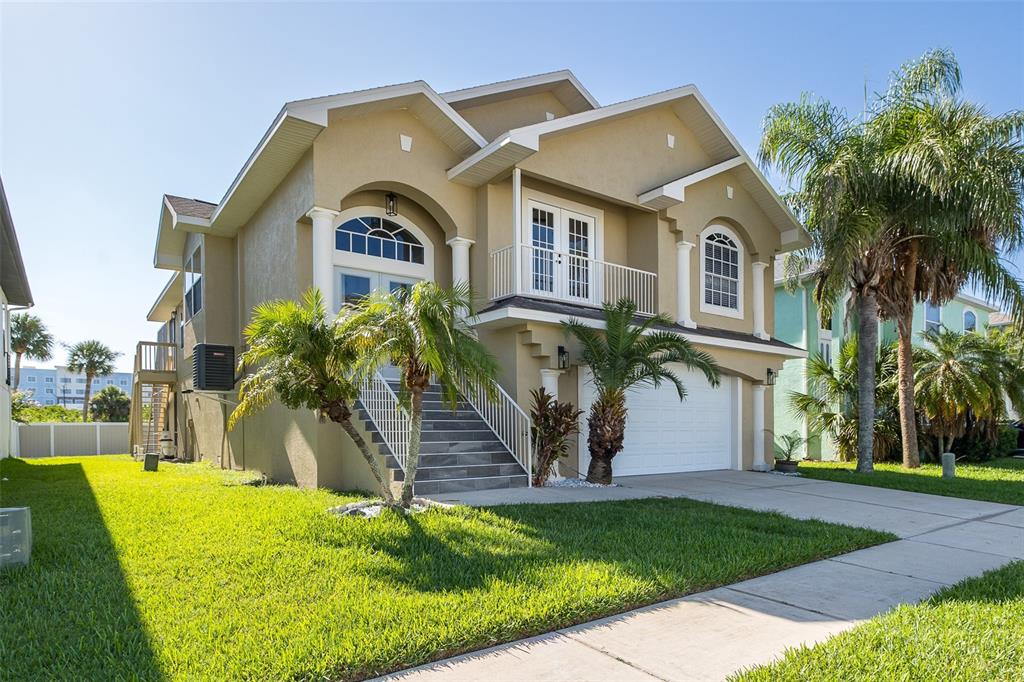 A two-story tan house with a raised entryway, a white garage door, and palm trees — 5416 JOBETH DRIVE, NEW PORT RICHEY, FL