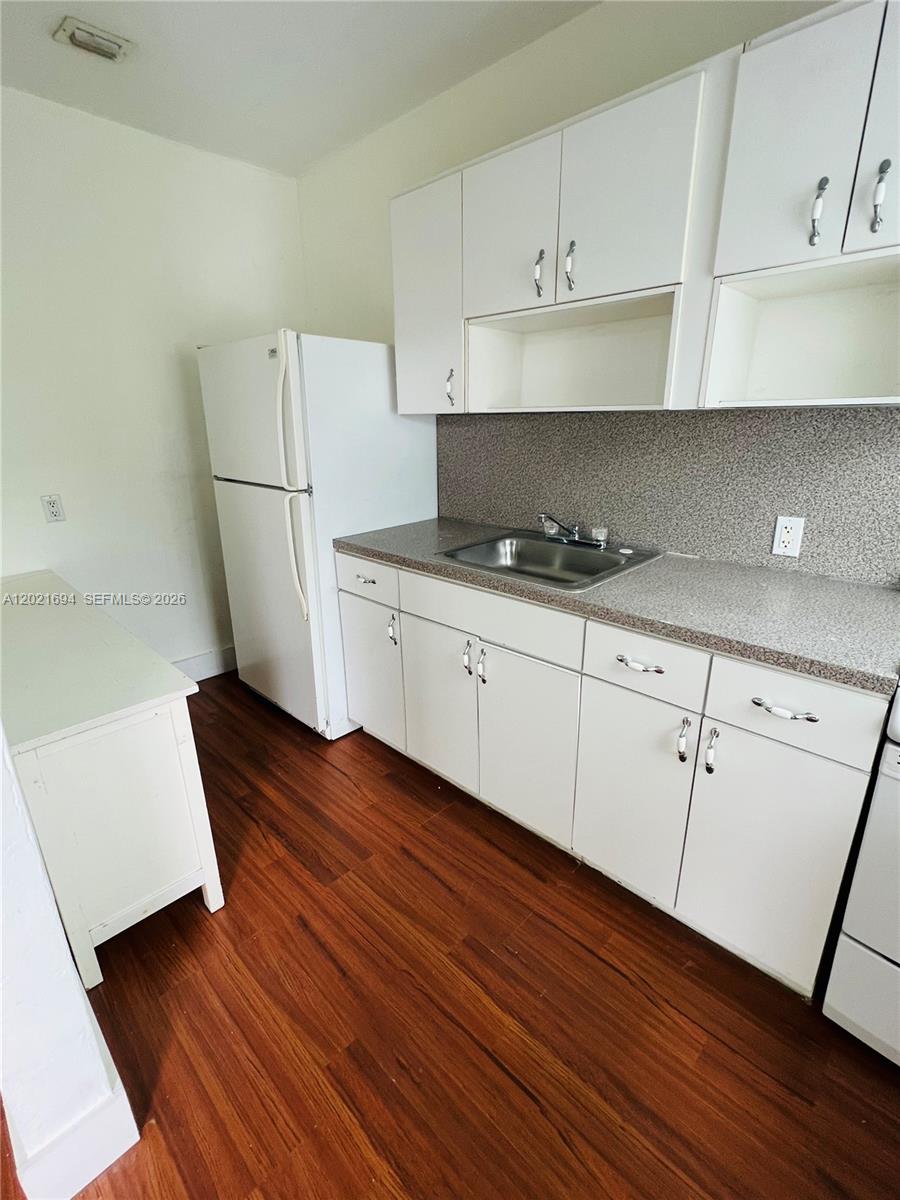 A kitchen features white cabinets, a stainless steel sink, a white refrigerator, and wood flooring — 850 81st St # 3, Miami Beach FL 33141, MIAMI BEACH, FL