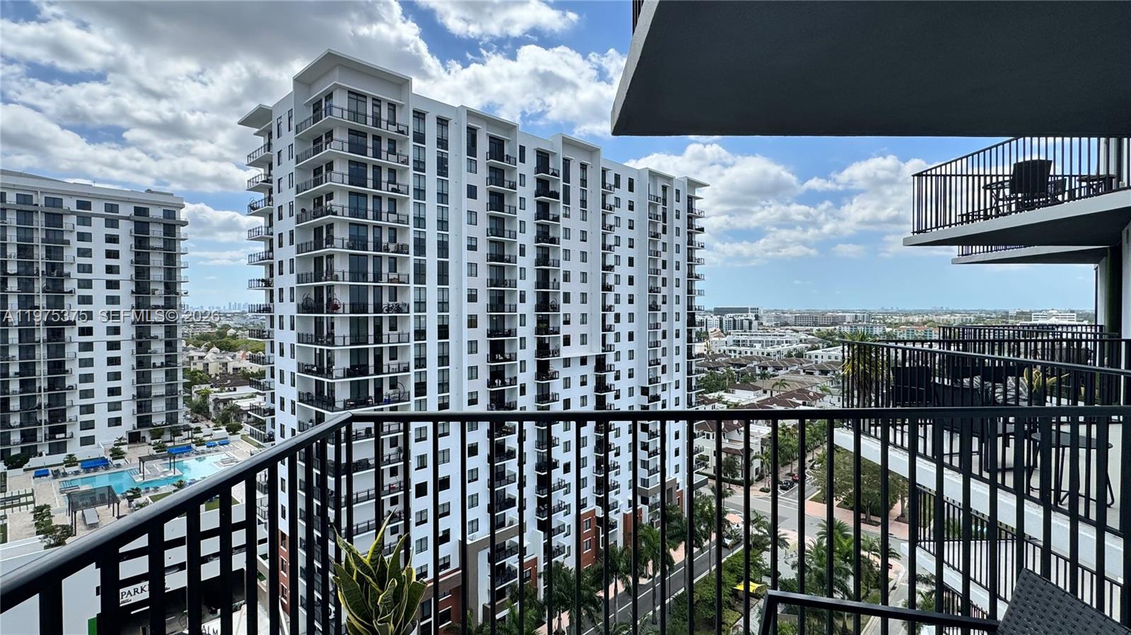 A view from a balcony overlooking a large white apartment complex and a swimming pool — 5252 NW 85th Ave # 1203, Doral FL 33166, DORAL, FL