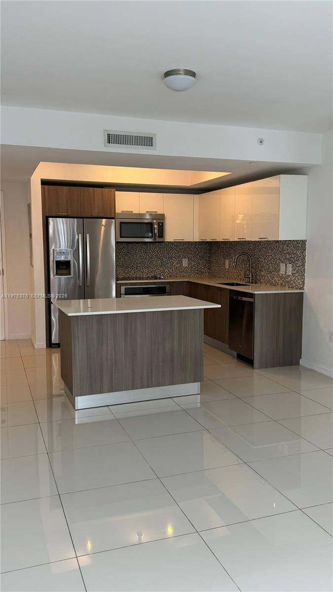 A modern kitchen features a central island, stainless steel appliances, and two-toned cabinetry — 5252 NW 85th Ave # 1203, Doral FL 33166, DORAL, FL