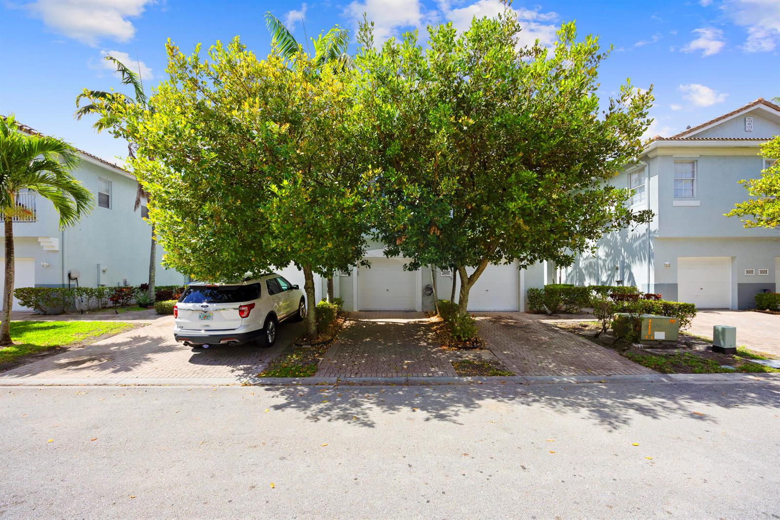 A white SUV is parked in the driveway of a two-story townhouse with trees — 3069 Laurel Ridge Circle, Riviera Beach FL 33404, RIVIERA BEACH, FL