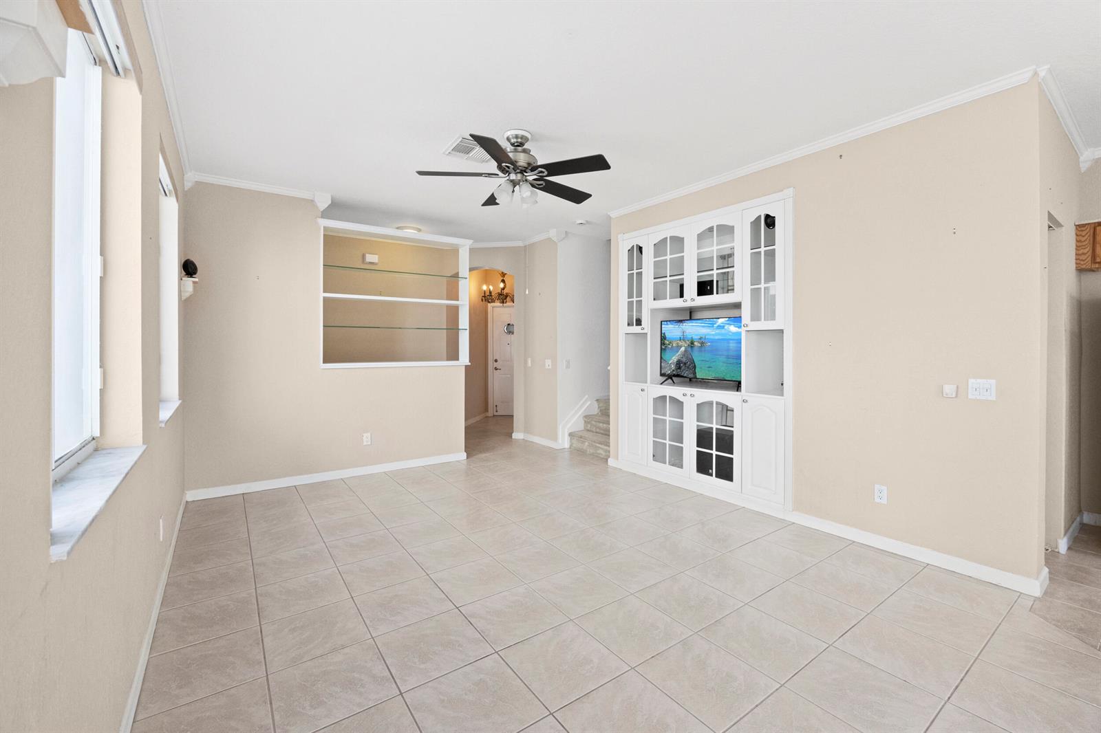A living room features tile flooring, a ceiling fan, built-in shelving, and a media cabinet — 3069 Laurel Ridge Circle, Riviera Beach FL 33404, RIVIERA BEACH, FL