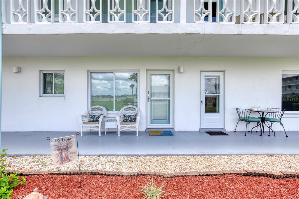 A ground-level patio with white wicker chairs, a small table, and two glass doors — 3013 N HALIFAX AVENUE UNIT B3, DAYTONA BEACH, FL