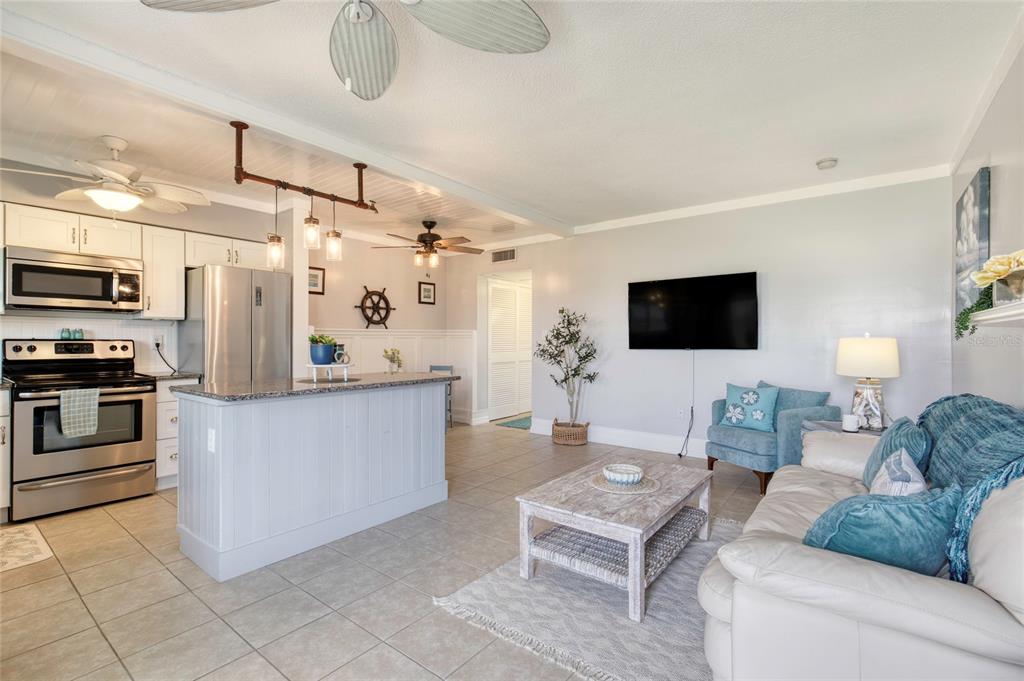 An open-concept kitchen and living area features stainless steel appliances, a breakfast bar, and tile flooring — 3013 N HALIFAX AVENUE UNIT B3, DAYTONA BEACH, FL