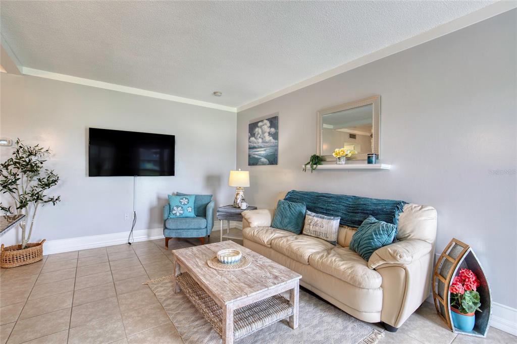 A living room features a beige sofa, a wooden coffee table, and a wall-mounted television — 3013 N HALIFAX AVENUE UNIT B3, DAYTONA BEACH, FL