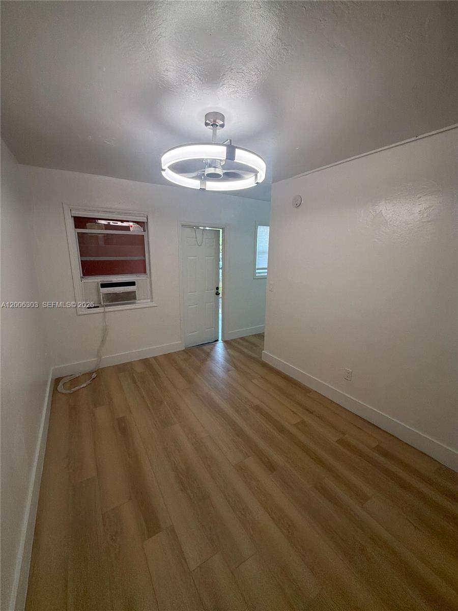 An empty room features light wood-look flooring, white walls, and a modern circular ceiling light — 3669 Thomas Ave # 9, Miami FL 33133, MIAMI, FL