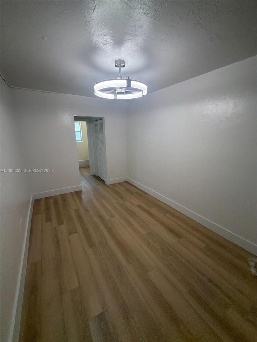 An empty room features white walls, light wood-look flooring, and a modern ceiling light fixture — 3669 Thomas Ave # 9, Miami FL 33133, MIAMI, FL