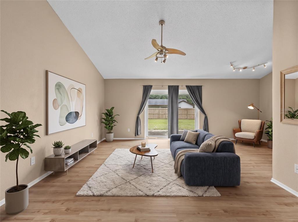 A living room features a blue sofa, a wooden coffee table, and sliding glass doors — 8040 CLOVERGLEN CIRCLE, ORLANDO, FL