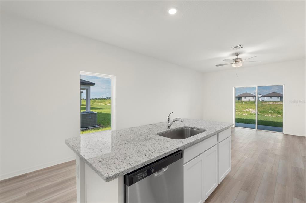 A kitchen island with a stainless steel sink and dishwasher sits in a bright room — 3636 AMANATSU STREET, LAKE ALFRED, FL