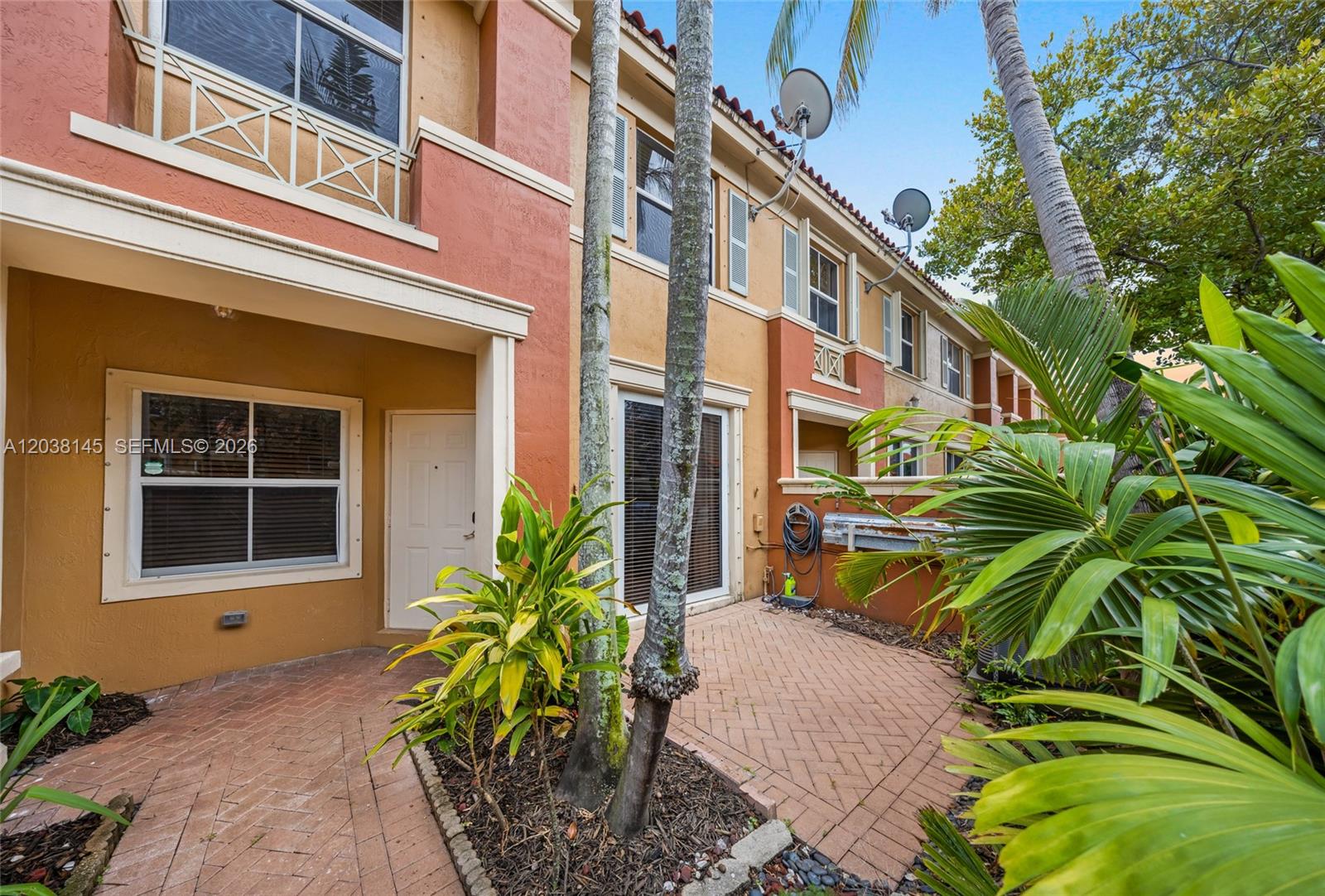 A paved patio area sits in front of a multi-story townhouse with palm trees — 11411 NW 60th St # 283, Doral FL 33178, DORAL, FL