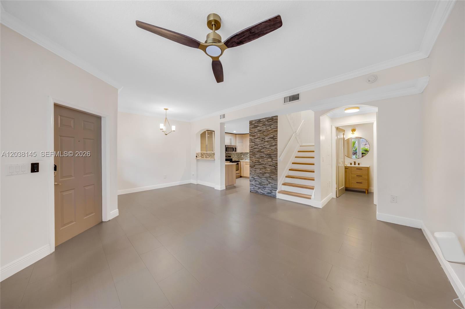 An open-concept living area features gray tile flooring, a stone accent wall, and a staircase — 11411 NW 60th St # 283, Doral FL 33178, DORAL, FL