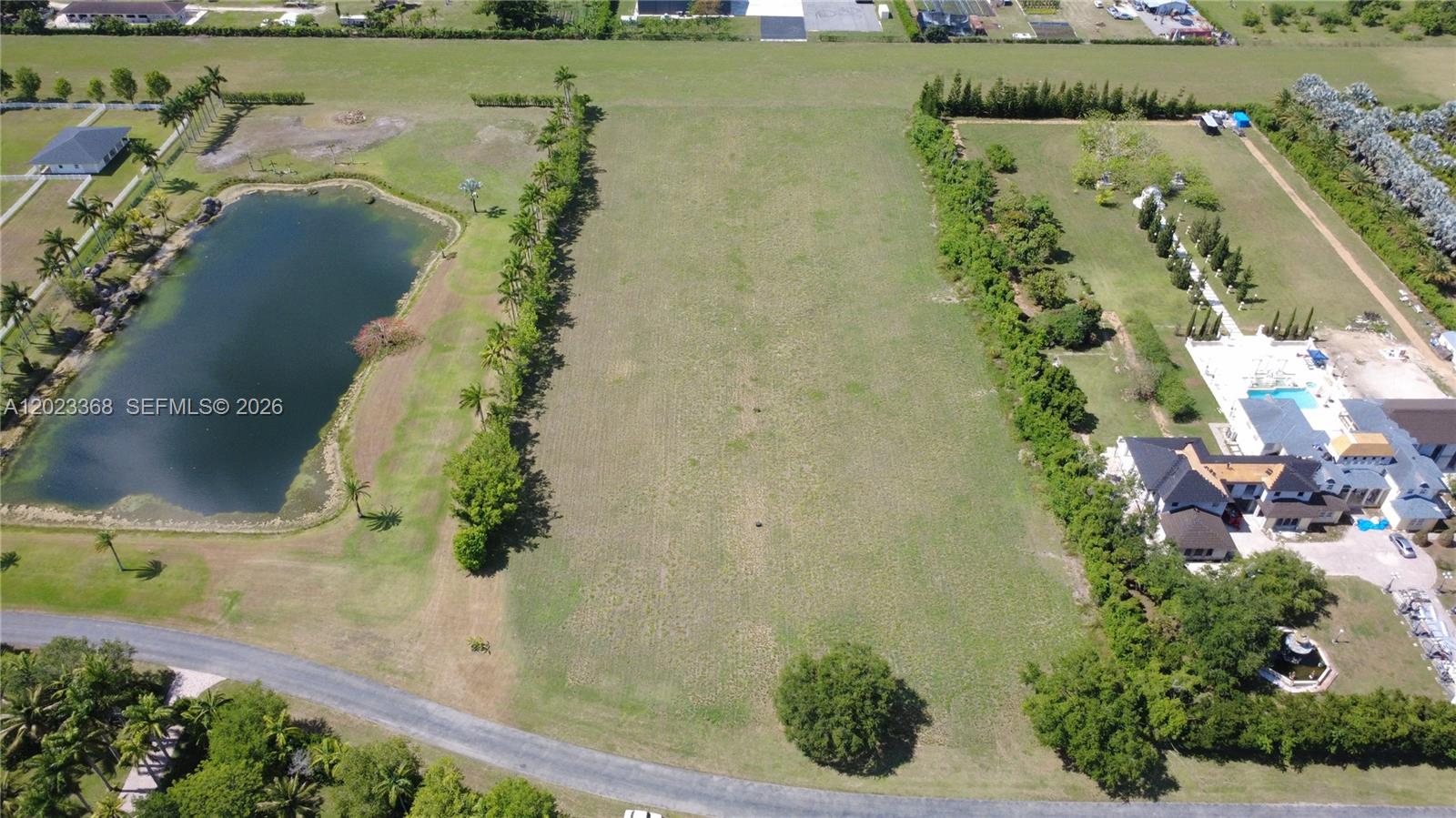 An aerial view shows a large, vacant rectangular lot situated between a pond and a residence — 18111 SW 158th St, Miami FL 33187, MIAMI, FL