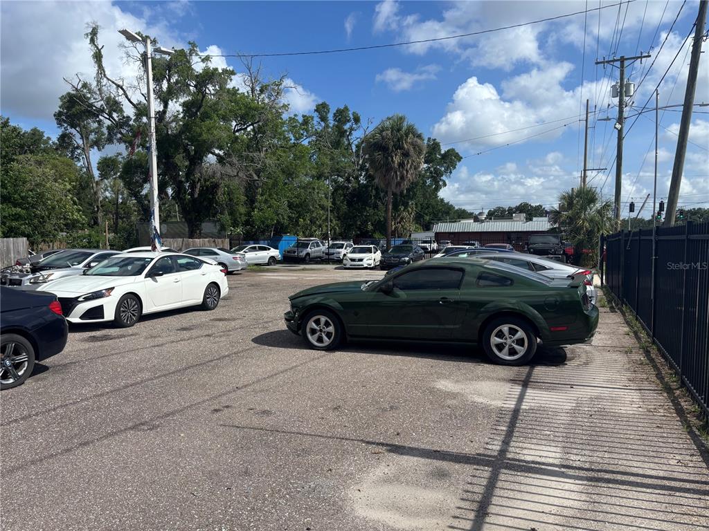 A gravel parking lot contains several parked cars, including a green Ford Mustang — 7402 N NEBRASKA AVENUE, TAMPA, FL