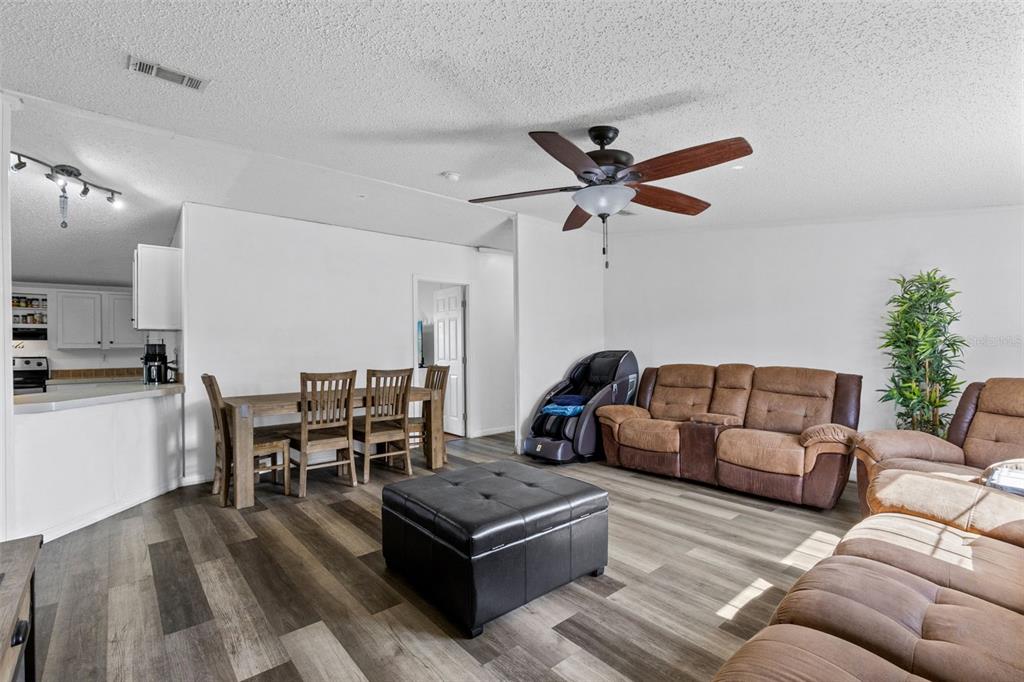 An open-concept living and dining area features wood-look flooring, a ceiling fan, and brown furniture — 35729 HUFF ROAD, EUSTIS, FL