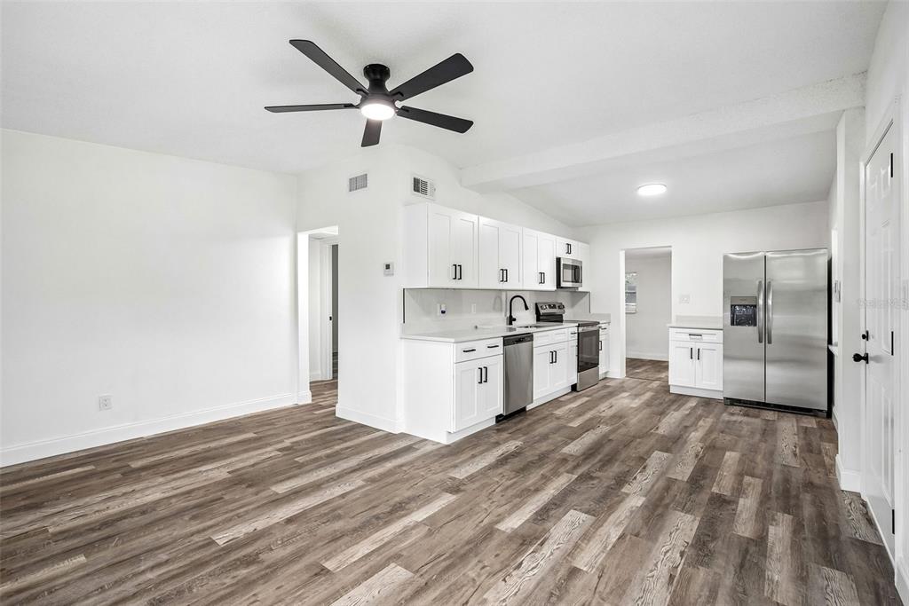 A bright, empty room features white walls, wood-look flooring, a ceiling fan, and multiple windows — 806 CITRUS STREET, ORLANDO, FL