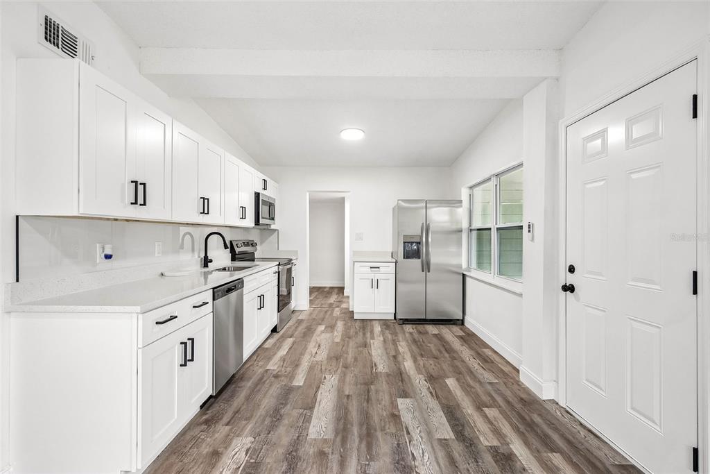 A bright living room with wood-look flooring, a ceiling fan, and an adjacent tiled bathroom — 806 CITRUS STREET, ORLANDO, FL