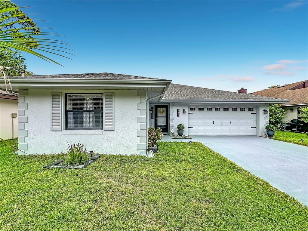 A single-story house with a white stucco exterior, a two-car garage, and a front lawn — 419 GREENFIELD ROAD, WINTER HAVEN, FL