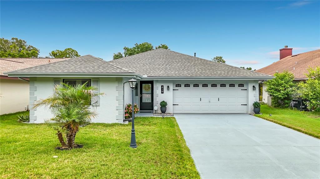 A single-story house with a white exterior, a two-car garage, and a front lawn — 419 GREENFIELD ROAD, WINTER HAVEN, FL
