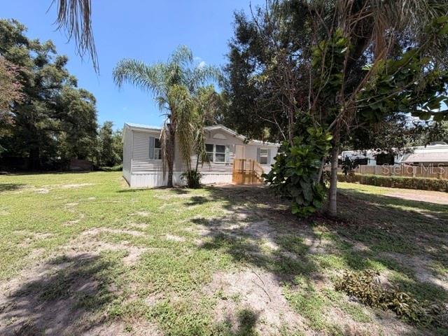 A single-story manufactured home sits on a grassy lot with palm trees and foliage — 4301 SHERWICK DRIVE, TAMPA, FL