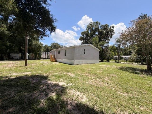 A light-colored manufactured home sits on a grassy lot with trees in the background — 4301 SHERWICK DRIVE, TAMPA, FL