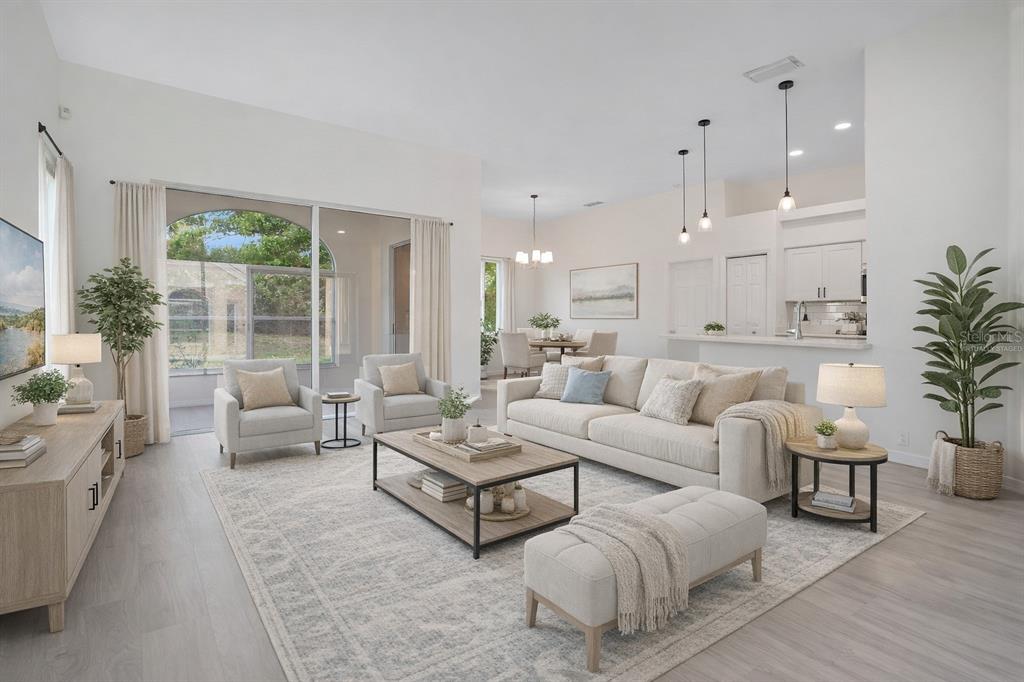 A bright, open-concept living room with light wood floors, neutral furniture, and a kitchen view — 8533 GATEWAY COURT, ENGLEWOOD, FL