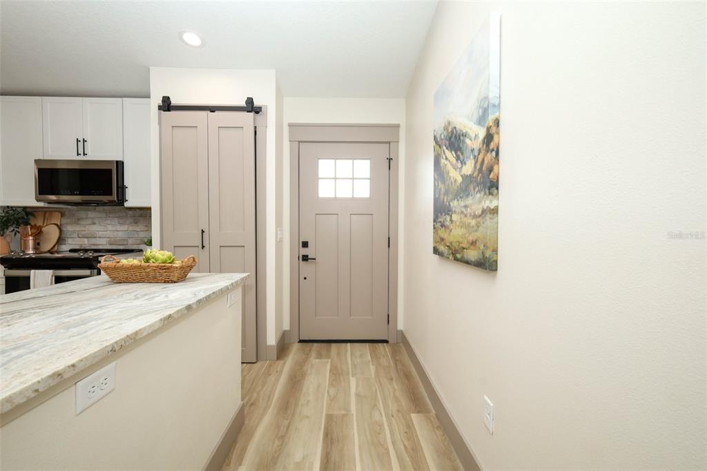 A kitchen with a stone countertop and a barn-style door leading to an entryway — 940 S DEAN CIRCLE, DELTONA, FL