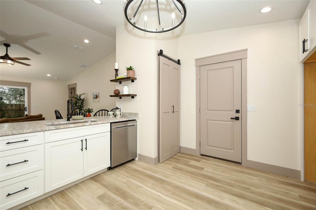 A kitchen with white cabinets, stainless steel appliances, and a light-colored door with barn hardware — 940 S DEAN CIRCLE, DELTONA, FL